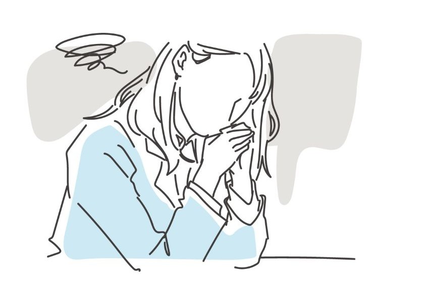 机に肘をつき落ち込む女性