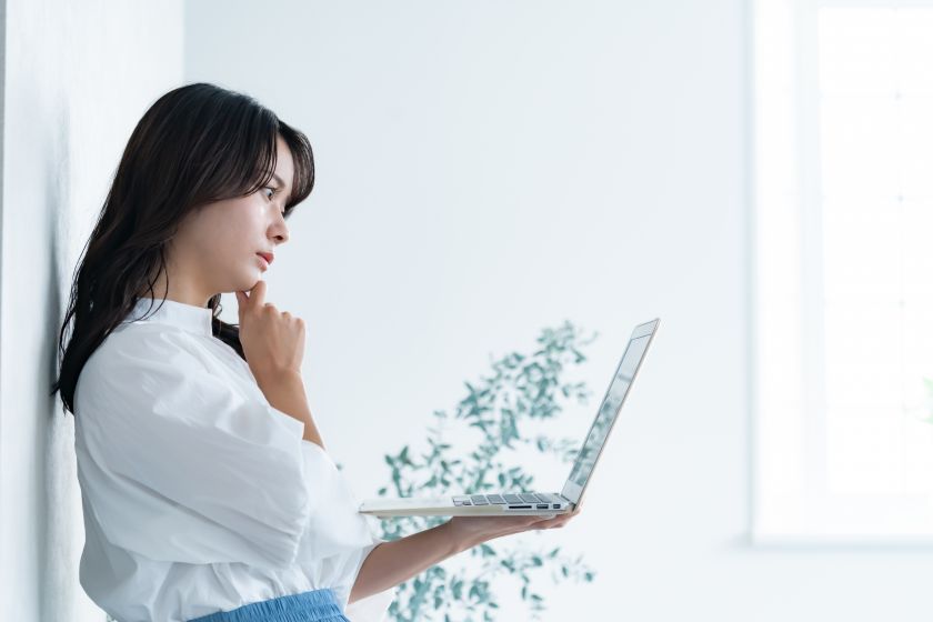 ノートPCを持って悩む若い女性